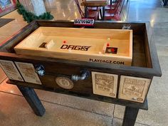 an old fashioned wooden game table with beer bottles in the drawer and two empty glasses on top