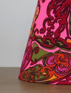 a pink lamp shade sitting on top of a wooden table