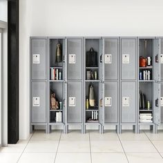 a row of lockers in a room with white tile flooring and doors open