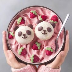 a person holding a bowl with some food in it and strawberries on the side