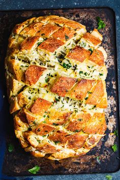 a cheesy bread dish is shown on a baking sheet with parmesan cheese and herbs