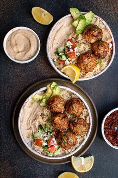 two bowls filled with food next to dipping sauce and lemon wedges on the side