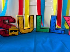 the letters are made out of legos and have sunglasses on them, along with streamers