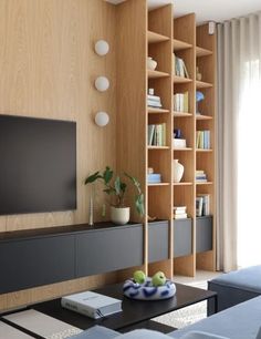 a living room filled with furniture and a flat screen tv on top of a wooden shelf