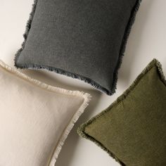 three different colored pillows on a white surface