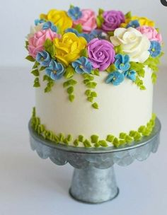 there is a cake decorated with flowers on the top and bottom tier, sitting on a stand