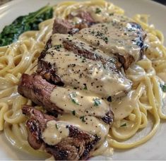 some meat and noodles on a plate with gravy over it, as well as broccoli