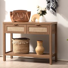 a wooden table with two baskets and a handbag on it next to a vase