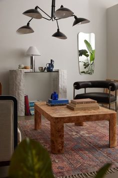 a living room filled with furniture and a wooden coffee table in front of a mirror