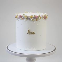 there is a white cake with flowers on the top and an arn written in gold