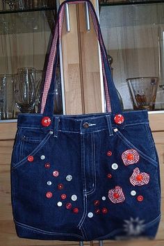 a denim purse with red and white buttons is on display in front of a glass case