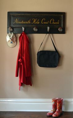 a coat rack with two coats hanging from it's hooks, and a pair of rubber boots on the floor