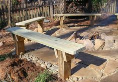 a wooden bench sitting on top of a stone patio next to a fire pit and fence