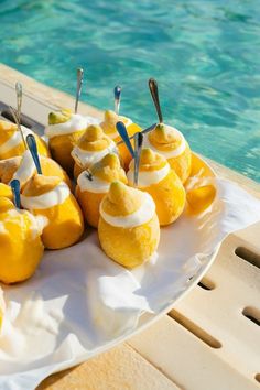 some lemons are sitting on a plate by the pool with toothpicks stuck in them