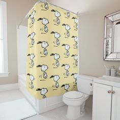 a bathroom with a yellow shower curtain that has sheep on it and is next to a toilet