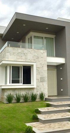 a house with steps leading up to the front door and grass in front of it