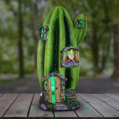 a green cactus sitting on top of a wooden table next to a gnome's house