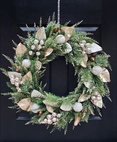 a christmas wreath hanging on a door with ornaments and greenery in front of it