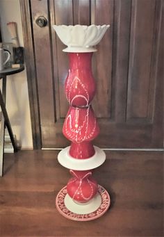 a red and white vase sitting on top of a wooden table next to a door