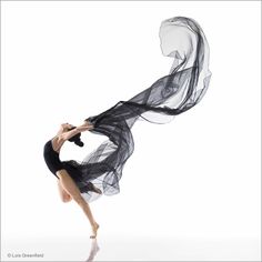 a woman is dancing with black veils on her head