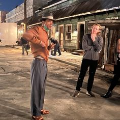 three people standing in the middle of an old town at night, one holding a microphone