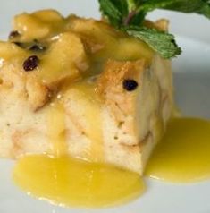 a piece of cake on a white plate with syrup and green leaf garnish