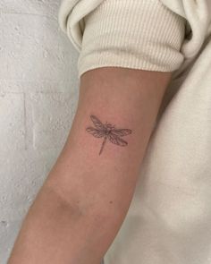 a small dragonfly tattoo on the arm