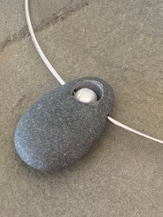 a rock with a light attached to it sitting on the ground next to a cord