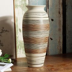 a white vase sitting on top of a wooden table next to a framed photo and flowers