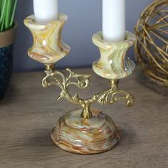 two white candles sitting on top of a wooden table