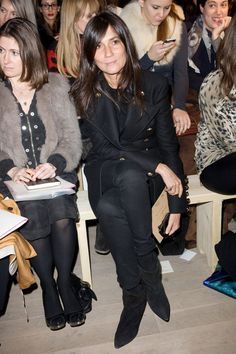 two women sitting next to each other in front of a crowd at a fashion show