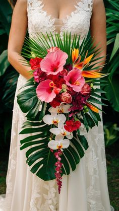 a woman in a wedding dress holding a large bouquet with pink and orange flowers on it