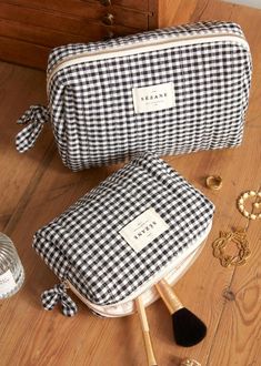 two black and white checkered bags sitting on top of a wooden floor next to jewelry