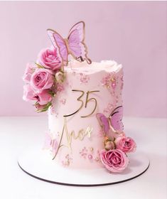 a pink birthday cake decorated with flowers and butterflies