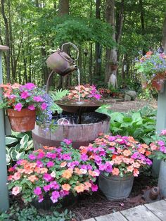 an outdoor fountain surrounded by potted plants and flowers in the foreground is a wooden deck