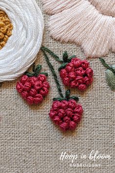 three crocheted cherries sitting on top of a table next to some yarn