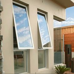 three windows with sky reflected in them on the side of a house