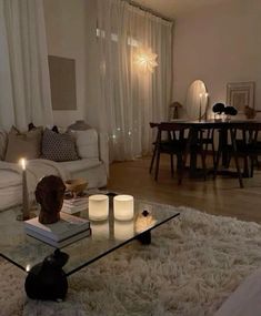 a living room filled with lots of furniture and candles on top of a glass table