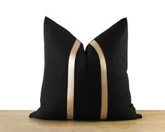 two black and gold pillows sitting on top of a wooden table