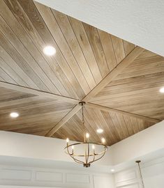 a chandelier hanging from the ceiling in a room with white walls and wood paneling