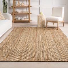 a living room area with white couches and an area rug on the floor that is made from natural materials