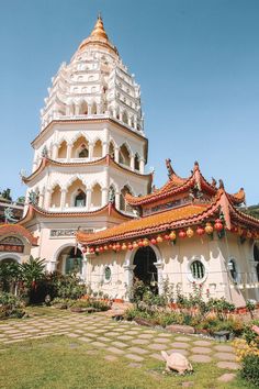 a tall white building sitting next to a lush green field