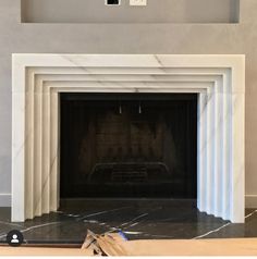 an empty fireplace with white marble surround