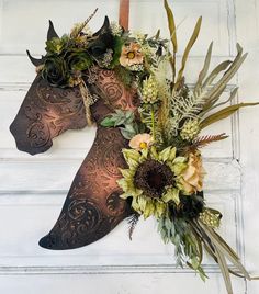 a horse head decorated with flowers and greenery hangs on the wall in front of a white door