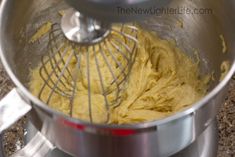 a metal bowl filled with yellow batter on top of a counter next to a whisk