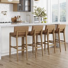 a kitchen with white walls and wooden flooring next to a bar stool set on top of a hard wood floor