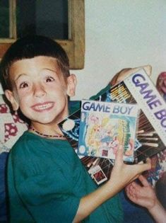 a young boy is holding up some games