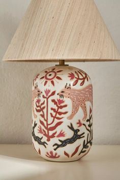 a lamp that is sitting on a table next to a white wall with red and black designs