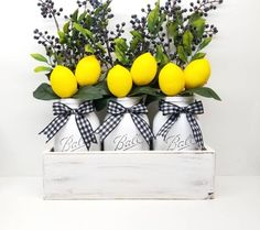 four lemons are sitting in white jars with black ribbon