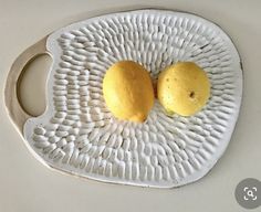 two lemons on a white plate with holes in the middle and one is cut in half